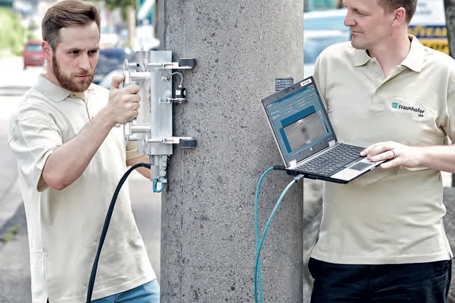 Zwei Prüfer untersuchen einen Betonmast mit dem BetoFLUX-Handgerät